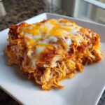 Close-up of a serving of moist crockpot chicken enchilada casserole topped with melted white and cheddar cheese.