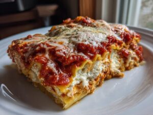 A generous slice of crockpot ravioli lasagna no meat layered with cheese and rich tomato sauce, served on a white plate.