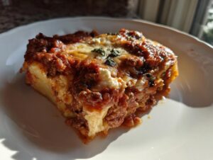 A close-up of a hearty slice of crockpot ravioli lasagna with ricotta cheese, topped with meat sauce and melted cheese.