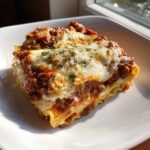 A perfectly layered slice of crockpot ravioli lasagna with ricotta cheese, topped with melted mozzarella and parsley.
