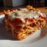 A hearty slice of crockpot ravioli lasagna layered with sauce, cheese, and pasta, topped with melted mozzarella.