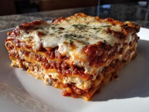 A thick, layered slice of crockpot ravioli lasagna topped with melted mozzarella and parsley on a white plate.