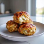 A stack of four golden brown feta stuffed greek chicken meatballs showing melted white feta cheese inside.