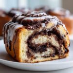 Close-up of a fluffy nutella rolls slice showing the swirled chocolate filling and white icing drizzle.