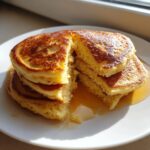 A stack of fluffy pancakes from scratch, cut open to show the texture, drizzled with golden syrup.