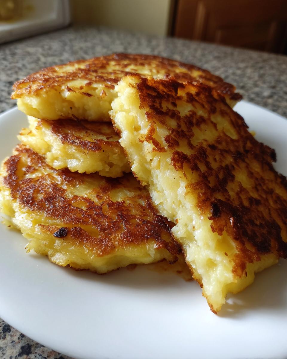 A stack of four golden-brown, crispy mashed potato pancakes served on a white plate.