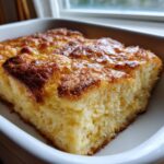 Close-up of a golden-brown slice of baked hawaiian roll french toast in a white dish.