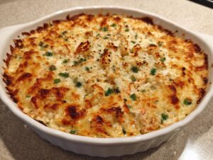 A freshly baked, bubbling hot Joe's Crab Shack Crab Dip with a golden-brown, cheesy crust in a white oval dish.