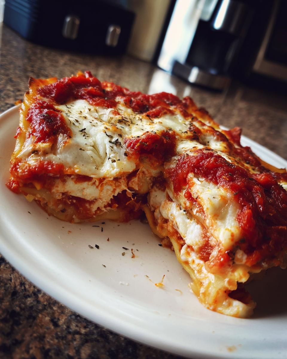 A close-up of a delicious slice of lazy day crockpot ravioli lasagna layered with cheese and marinara sauce.