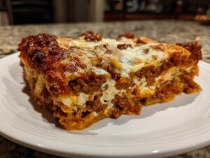 A close-up of a thick, cheesy slice of million dollar lasagna featuring rich meat sauce and browned cheese topping.