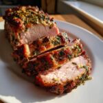 Close-up of a juicy pork loin roast recipe, sliced and showing a beautiful herb crust.