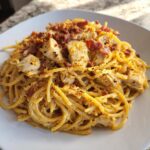 A close-up of a plate piled high with creamy Monterey chicken spaghetti topped with chunks of seasoned chicken and crispy bacon bits.