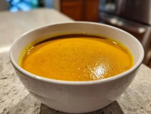 Close-up of a creamy, vibrant orange panera butternut squash soup served in a white bowl.