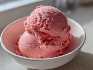 Two scoops of bright pink 2-ingredient summer sherbet served in a small white bowl.