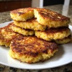 A stack of perfectly golden-brown, crispy polish potato pancakes piled high on a white plate.