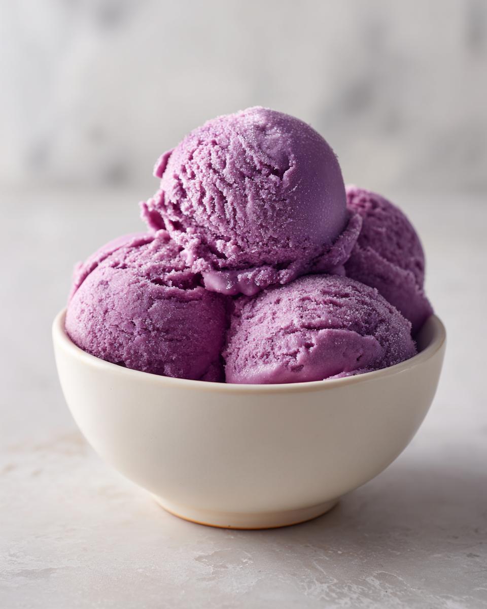 Four scoops of bright purple, icy summer sherbet piled high in a small white bowl.