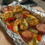 Close-up of cooked shrimp and sliced sausage mixed with peppers in a foil pack, perfect for shrimp and sausage foil packs.