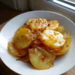 Close-up of tender, sliced slow cooker lipton onion potatoes seasoned with herbs in a white bowl.