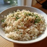 A white bowl filled with fluffy texas roadhouse seasoned rice, topped with fresh parsley and spices.