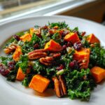 Close-up of a vibrant healthy fall salad featuring kale, roasted sweet potatoes, pecans, and dried cranberries.