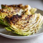 Close-up of charred and seasoned grilled cabbage steaks served on a light plate.