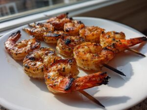 Close-up of perfectly cooked, seasoned grilled shrimp skewers resting on a white plate, showing char marks.