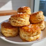 A stack of freshly baked honey butter biscuits drizzled with glaze and topped with flaky sea salt.