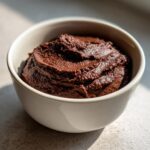 A close-up of thick, rich chocolate dessert hummus served in a light-colored bowl.