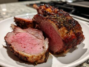 Close-up of perfectly cooked Roast leg of lamb, showing a deep pink, medium-rare center and a dark, herb-crusted exterior.