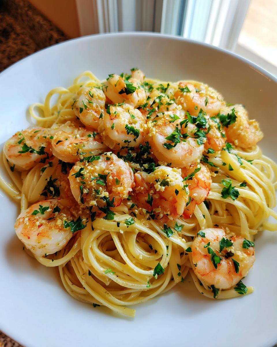 A close-up of homemade Shrimp Scampi served over linguine pasta, generously topped with garlic and fresh parsley.